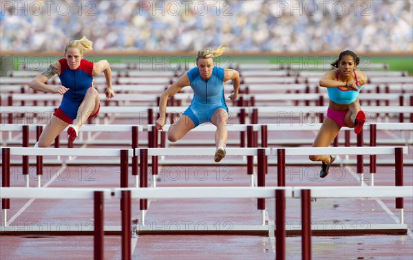 Runners jumping hurdles in race