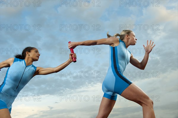 Runners passing baton in relay race