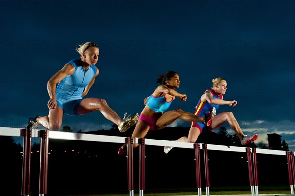 Runners jumping hurdles in race