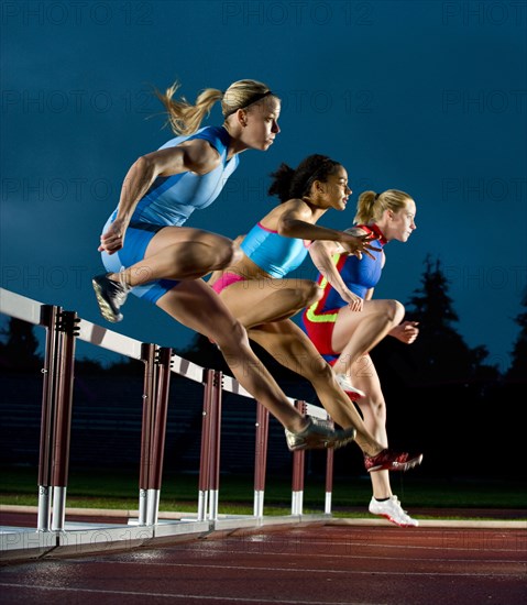 Runners jumping hurdles in race