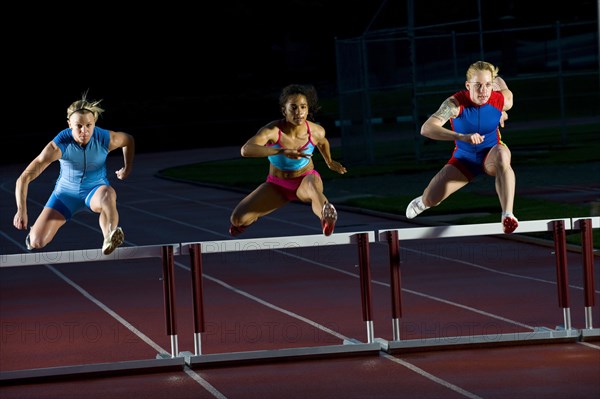 Runners jumping hurdles in race