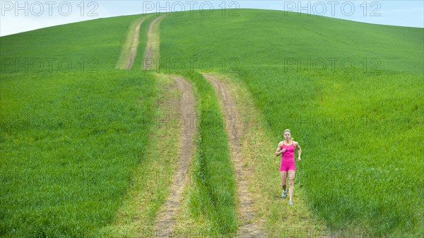 Caucasian woman running on path through field