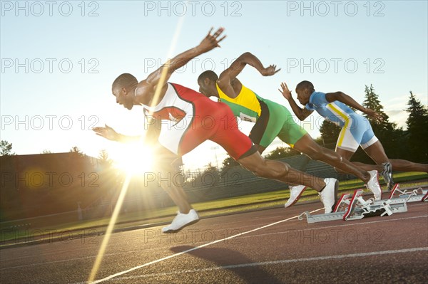 Black runners taking off from starting block in race