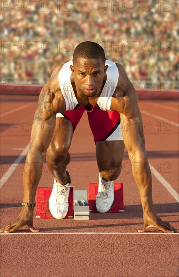 Black runner at starting block in race