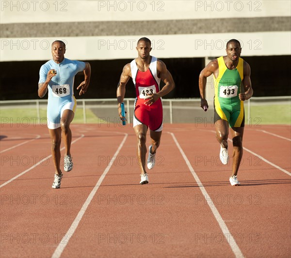 Black runners running on track in relay race