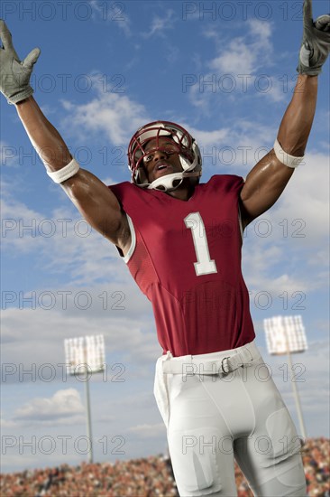 Black football player with arms raised