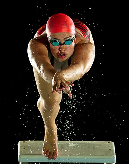 Mixed race swimmer diving off starting block