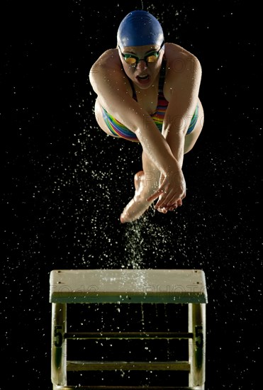 Caucasian swimmer diving off starting block