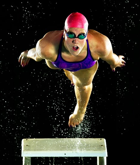 Caucasian swimmer diving off starting block