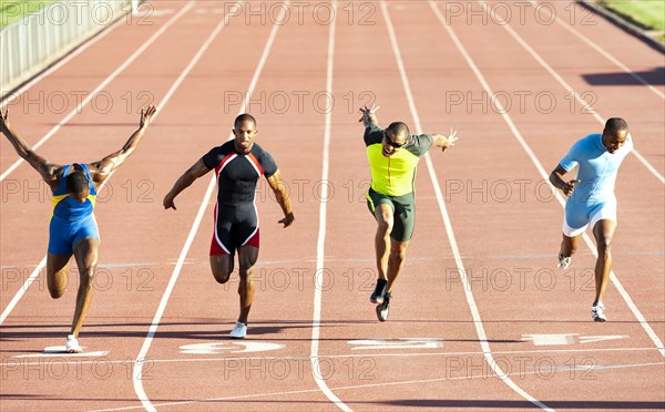 Runners running across finish line on track in race