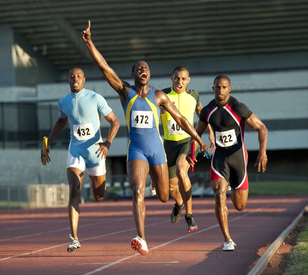 Relay racer crossing finish line on track in race