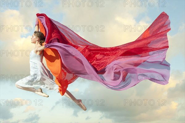 Caucasian woman floating through air with scarves