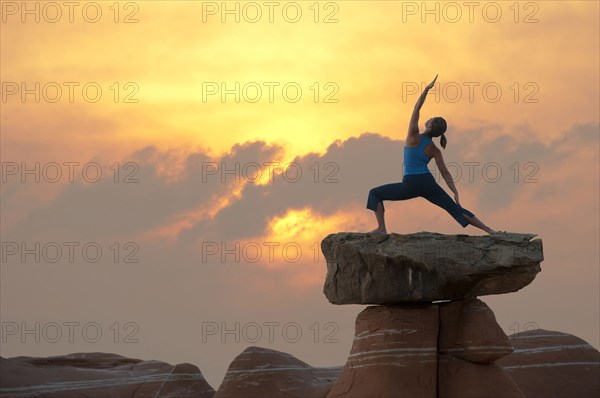 Caucasian woman practicing yoga on top of rock formation