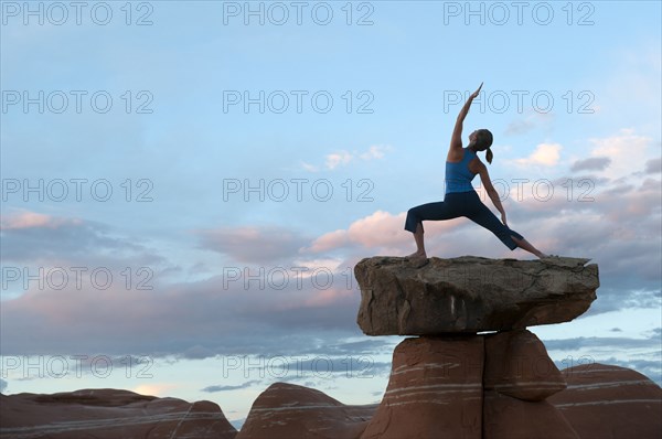 Caucasian woman practicing yoga on top of rock formation