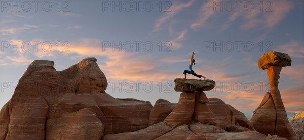 Caucasian woman practicing yoga on top of rock formation