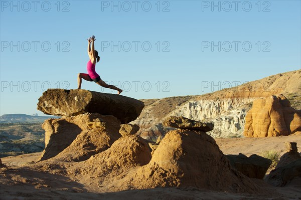 Caucasian woman practicing yoga on top of rock formation