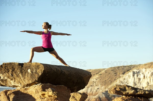 Caucasian woman practicing yoga on top of rock formation