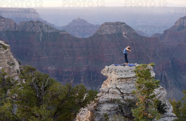 Caucasian woman practicing yoga on top of rock formation