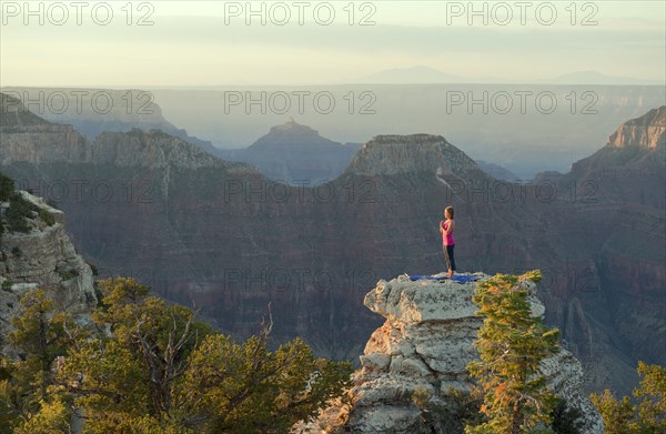 Caucasian woman practicing yoga on top of rock formation