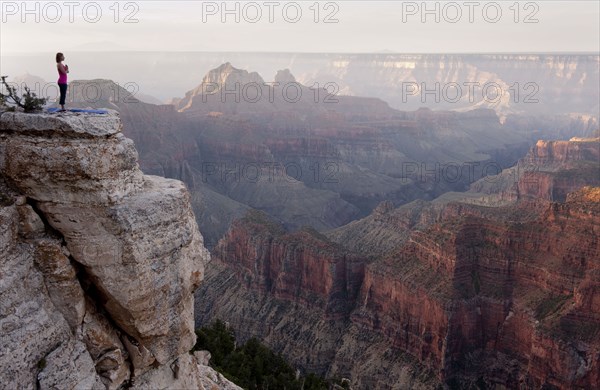 Caucasian woman practicing yoga on cliff near canyon