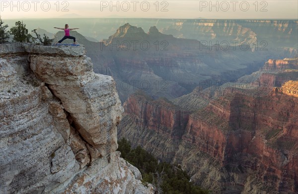 Caucasian woman practicing yoga on cliff near canyon
