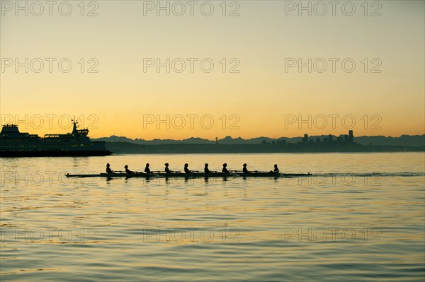 Team rowing boat in bay