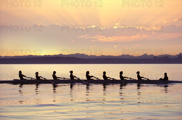 Team rowing boat in bay