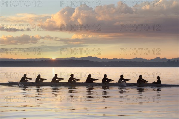 Team rowing boat in bay