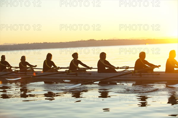 Team rowing boat in bay