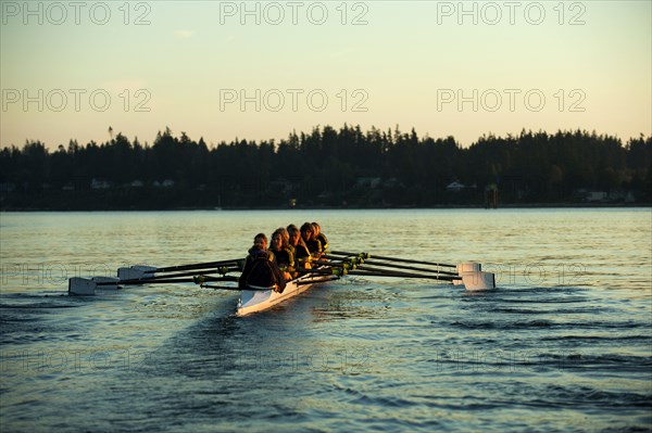 Team rowing boat in bay