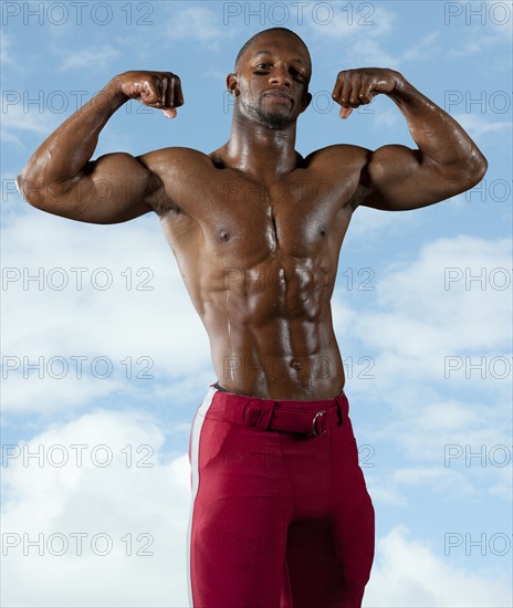 Black football player flexing muscles