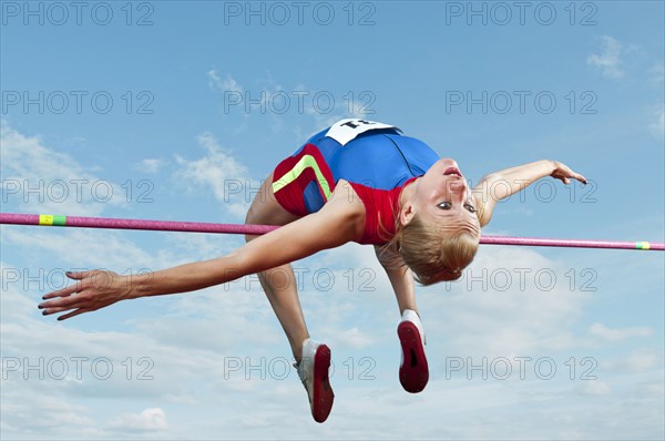 Caucasian athlete jumping over bar