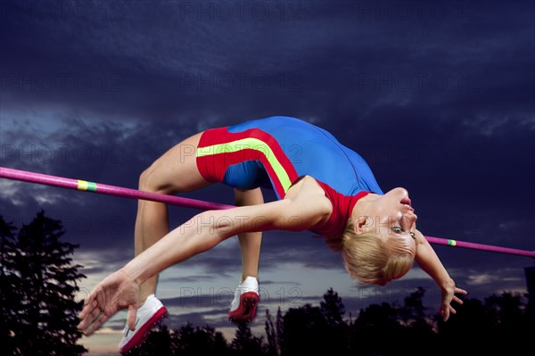 Caucasian athlete jumping over bar