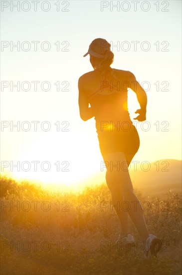 Caucasian woman running at sunset