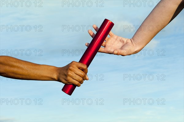 Runner passing baton to teammate