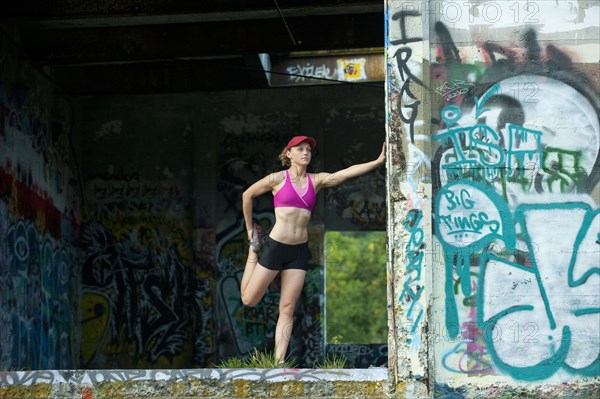 Caucasian woman stretching in abandoned loading dock