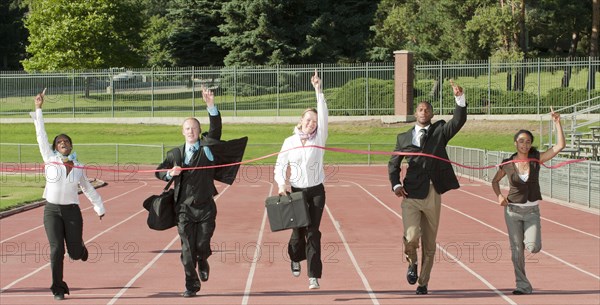 Business people running across track finish line