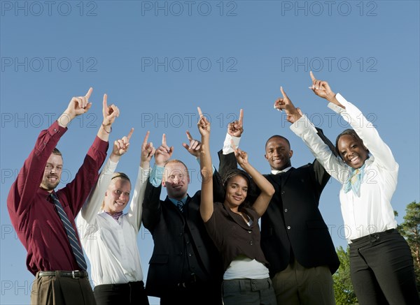 Business people standing together with arms raised