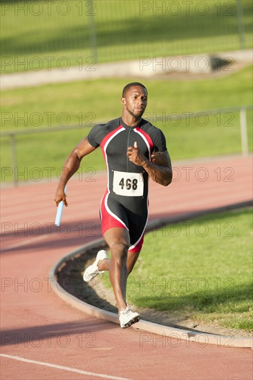 Black runner carrying baton in relay race