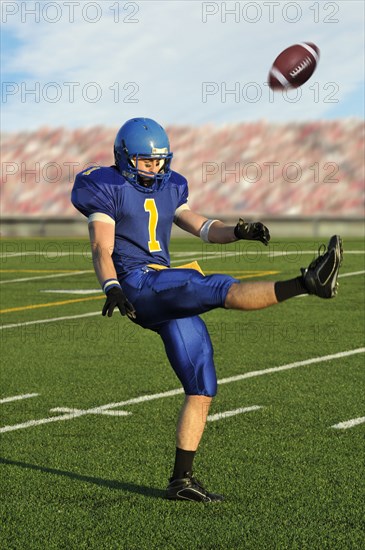 Caucasian football player kicking football