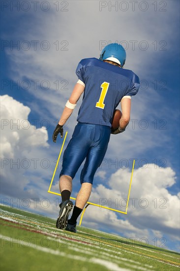 Caucasian football player carrying football