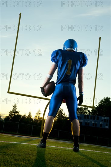 Caucasian football player standing with football