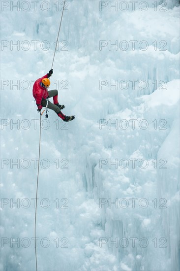 Caucasian man rappelling down ice wall