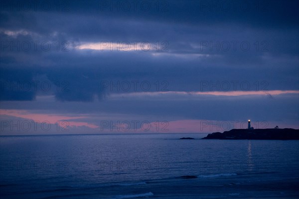 Lighthouse beaming from coastline at night