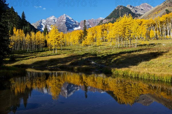 Yellow trees and mountains reflected in still water