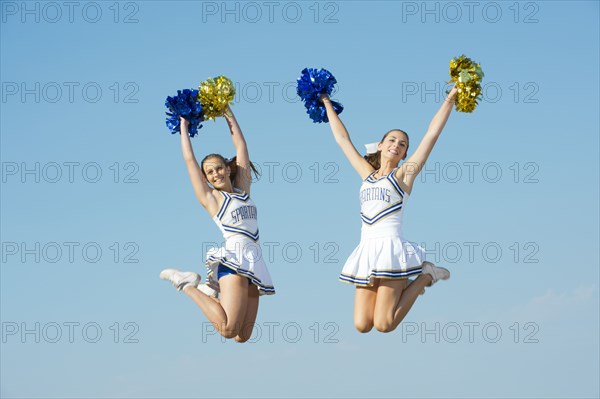 Caucasian cheerleaders jumping in mid-air