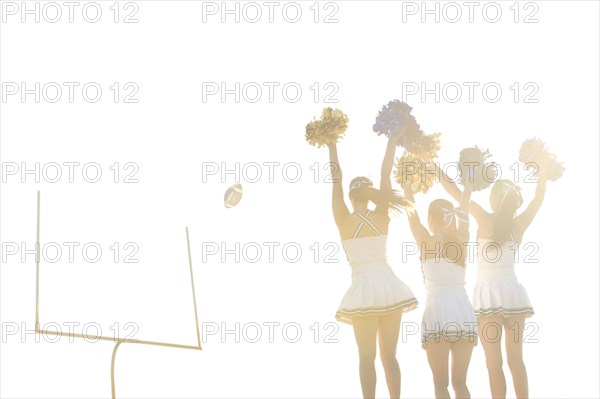 Caucasian cheerleaders on sidelines at football game