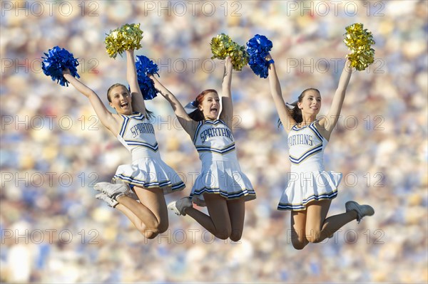Caucasian cheerleaders jumping in mid-air