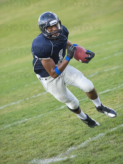 African American football player carrying ball