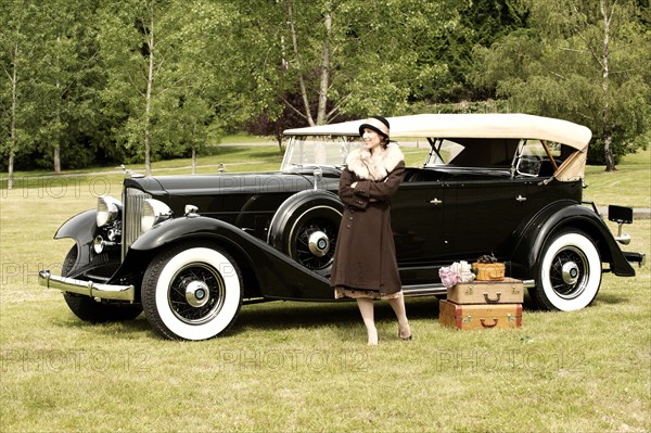 Caucasian woman with luggage by vintage car